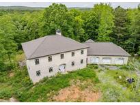 An aerial view of a large two-story house with an attached garage surrounded by trees at 7 Perkins Mountain Rd, Kingston, GA 30145