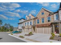 Beautiful multi-level townhomes showcasing stone and brick facades with attached two-car garages at 116 Via Roma, Woodstock, GA 30188