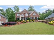 Charming two-story brick home with a manicured lawn and colorful, mature landscaping at 227 Cedarhurst Dr, Canton, GA 30115