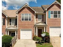 Charming townhome showcasing a brick facade, single-car garage, and neatly landscaped front yard under a bright sky at 5485 Sierra Trl, Atlanta, GA 30349