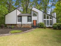 Striking home with modern architecture, multiple windows, a well-manicured lawn, and a stone accent wall at 4514 Creekwood Nw Cir, Kennesaw, GA 30152
