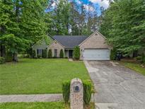 Charming home with brick and siding exterior, well-manicured lawn, and mature trees at 1642 Ashmar Sw Ln, Marietta, GA 30064