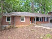 A single-story brick home with a dark roof and overgrown landscaping at 668 Lynn Sw Cir, Atlanta, GA 30311
