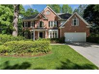 Beautiful two-story brick home featuring a well-manicured lawn and mature trees for added curb appeal at 1575 Wynridge Pointe, Alpharetta, GA 30005