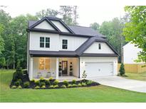 Charming two-story home featuring white siding, black trim, a covered porch, and a well-manicured front yard at 2610 Lisa Sw Dr, Atlanta, GA 30311