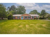 Charming one-story brick home with a spacious front yard and inviting blue door at 599 Honey Creek Rd, Conyers, GA 30094
