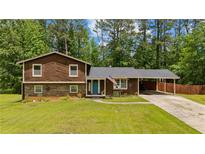 Charming split-level home with a well-manicured lawn, attached carport, and inviting blue front door at 173 Avalon Way, Riverdale, GA 30274