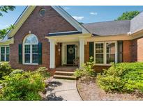 Charming brick home featuring a welcoming entrance, complete with lovely wreath and well-maintained landscaping at 1820 Habersham Gate Dr, Cumming, GA 30041
