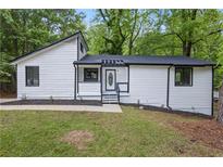 Charming renovated home featuring black trim, white siding, and a well-manicured front lawn at 9438 Cedar Creek Pl, Douglasville, GA 30135