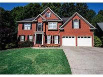 Beautiful two-story brick home boasts an attached two car garage, verdant lawn, and meticulously manicured shrubbery at 308 Forkwood Trl, Woodstock, GA 30189