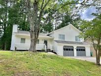 Inviting two-story home with a two-car garage, white siding, a covered porch, and mature trees at 3045 Revere Cir, Snellville, GA 30039