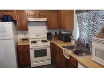 Cozy kitchen featuring wooden cabinets, white appliances, and a window with a patterned curtain at 335 Chase Woods Cir, Jonesboro, GA 30236