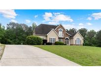 Charming two-story home with a stone and stucco facade, arched entryway, balcony, and lush landscaping at 11440 Azalea Trl, Hampton, GA 30228