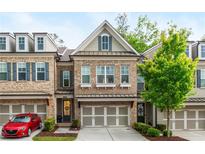 Charming brick townhome featuring a two-car garage and manicured landscaping at 2024 Towneship Trl, Roswell, GA 30075