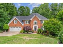Charming two-story brick home with a well-manicured lawn, lush landscaping, and a two-car garage at 420 Windswept Ct, Roswell, GA 30075