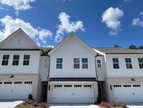 Charming townhome showcasing white siding, brick accents, and a well-maintained two-car garage with lovely landscaping at 2409 Malster Ln, Lawrenceville, GA 30043