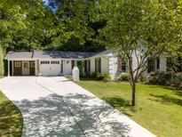 Charming single-story home featuring a white brick facade, dark shutters, manicured lawn and a spacious driveway at 3176 Gablewood Ct, Decatur, GA 30033
