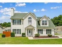 Charming two-story home with a manicured lawn, green roof, and classic architectural details at 5273 High Tide Ct, Atlanta, GA 30349