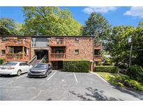 Brick condo building featuring small wooden balconies, well-maintained landscaping, and a parking lot at 323 8Th Ne St # 7, Atlanta, GA 30309