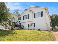Charming two-story home with a large front yard, stairs leading to the entrance and traditional black shutters at 7760 Poppy Dr, Winston, GA 30187