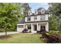 Charming two-story home with manicured lawn, white painted brick, dormer windows, and a welcoming front porch at 304 Meadowbrook Ne Dr, Atlanta, GA 30342