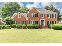 Charming brick home featuring a lush green lawn, manicured shrubs, and classic black shutters, offering curb appeal at 395 Clubfield Dr, Roswell, GA 30075