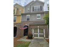 Charming townhouse with brick facade and attached garage, showcasing American flag at 106 Trailside Way, Hiram, GA 30141