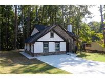 Charming home featuring stone accents, white siding, and a well-manicured lawn surrounded by mature trees at 3563 Brenda Ct, Douglasville, GA 30135