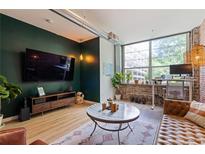Stylish living room with a brick accent wall, large window, and modern decor at 800 Peachtree Ne St # 8429, Atlanta, GA 30308