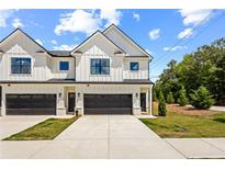 Charming new construction townhome with white siding, dark garage door, and landscaped front yard at 213 Starr Cir, Stockbridge, GA 30281