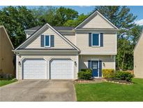 Charming two-story home featuring a two-car garage, well-manicured lawn and blue accent shutters at 5035 Pattingham Dr, Roswell, GA 30075