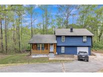Charming two-story home with a manicured lawn, attached garage, and a rustic porch with wood paneling at 3819 Shane Ct, Ellenwood, GA 30294