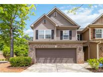 Charming two-story home featuring a brick facade and a two-car garage, set against a backdrop of lush greenery at 1945 Bay Beauty Ln # 10, Austell, GA 30106