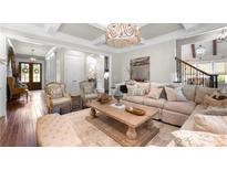Bright living room boasts beautiful chandelier lighting, hardwood floors, and coffered ceilings at 12980 Overlook Pass, Roswell, GA 30075