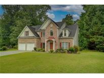 Charming two-story brick home with manicured lawn, lush landscaping, and a welcoming double door garage at 4942 Brown Leaf Dr, Powder Springs, GA 30127