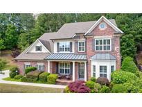 Charming two-story brick home with a covered front porch and beautifully landscaped yard at 621 Oakbourne Way, Woodstock, GA 30188
