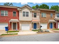 Townhomes with brick and vinyl siding, offering an attached garage, and landscaped surroundings at 5019 Lower Elm St, Atlanta, GA 30349