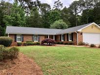 Charming brick home with a well-manicured lawn, mature landscaping, and a two-car garage at 1818 Brandy Woods Se Dr, Conyers, GA 30013