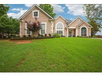 Charming home featuring a manicured lawn, elegant architectural details, and tasteful landscaping at 65 Wisteria Blvd, Covington, GA 30016