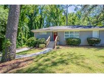 Charming single-story home features a gray brick exterior, green lawn and a red front door at 2755 Rockcliff Se Rd, Atlanta, GA 30316