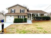 Charming two-story home with neutral siding, tidy landscaping, covered entry, and attached garage at 6325 Stablewood Way, Lithonia, GA 30058