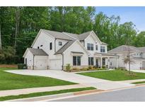 Stunning two-story white home with a three-car garage and well-manicured lawn surrounded by lush trees at 172 Aspen Hall Dr, Canton, GA 30115