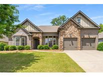 Charming home featuring a stone and brick facade, complemented by a well-manicured lawn and attached two car garage at 6995 Tybridge St, Cumming, GA 30040