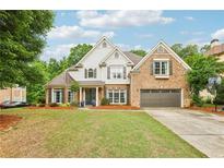 Beautiful two-story home with a brick facade, lush lawn, mature trees, and a two car garage at 3874 Lost Oak Dr, Buford, GA 30519