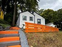 Exterior angle featuring a charming, light-colored house with an orange painted fence at 10 Rockmart Nw Dr, Atlanta, GA 30314
