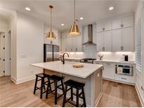 Bright kitchen features white cabinets, stainless steel appliances, pendant lighting, and a large center island with seating at 1006 Fendley St, Woodstock, GA 30188