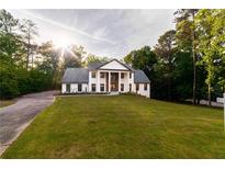 Stunning two-story home with a manicured lawn and elegant, column-lined entryway, surrounded by lush trees at 4 Bentley Trace Mnr, Atlanta, GA 30327