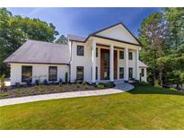 Beautiful two-story home with white brick, black trim, large columns, and a professionally landscaped front yard at 4 Bentley Trace Mnr, Atlanta, GA 30327