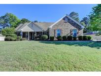 Charming single-story brick home with manicured lawn and mature trees at 1550 Misty Valley Dr, Lawrenceville, GA 30045