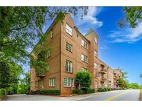Elegant brick condo building featuring manicured landscaping, and patriotic American flags displayed on the front lawn at 351 Ne Washington Ne Ave # 307, Marietta, GA 30060